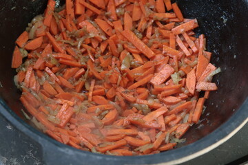 Carrots are stewed in a cauldron. Dishes cooked on fire. Eastern cuisine. Close-up. Selective focus. Copyspace