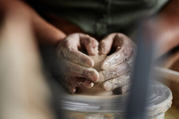 Front view closeup of female hands creating earthenware carefully shaping clay on pottery wheel...