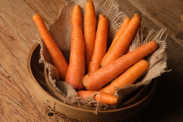 fresh carrots in a woven bamboo container lined with burlap. wortel. 