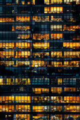 An office building at night, filled with glowing windows like the lights of an urban cityscape, captures the symmetrical arrangement and grid effect. 