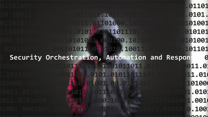 Cyber attack security orchestration, automation and response text in foreground screen, anonymous hacker hidden with hoodie in the blurred background. Vulnerability code on editor program.