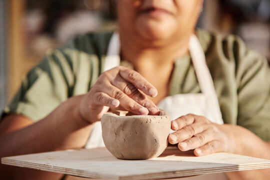 Close up detail shot of senior woman carefully shaping clay piece enjoying pottery class in sunlight copy space