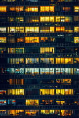 An office building at night, filled with glowing windows like the lights of an urban cityscape, captures the symmetrical arrangement and grid effect. 