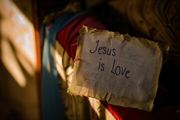 Handwritten Sign Reading 'Jesus is Love' in Warm Light with Textured Background