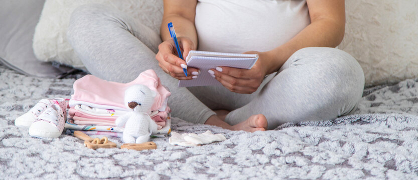 A pregnant woman collects baby things. Selective focus.