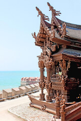 Detailed wooden temple by the sea with sunlight and intricate sculptures, Sanctuary Of Truth, Pattaya, Thailand