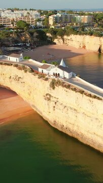 Aerial view of the cape in Atlantic ocean with beautiful church Senhora de Nossa, Algarve region coastline, South Portugal. Chapel Nossa Senhora da Rocha in Portugal at sunrise