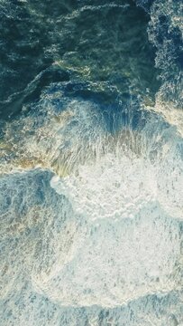 Vertical Screen: Enjoy a stunning vertical aerial view of crashing ocean waves in Nazare, Portugal, ideal for scenic backgrounds. Perfect for capturing the beauty of the sea and its dynamic waves