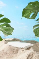 The blank podium with plaster material placed on sand side with monstera green leaves decorated...