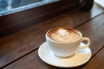 Hot coffee latte with latte art milk foam in cup mug on wood desk on top view. As breakfast In a coffee shop at the cafe,during business work concept,vintage style