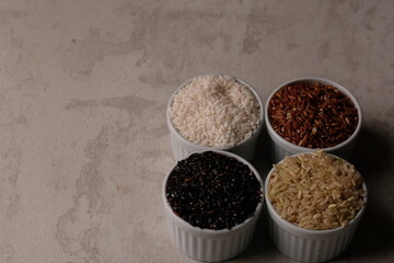 various rice in a white ceramic bowl. There are brown rice, black rice, brown and white. Rice is the staple food of most Asians. Oryza sativa. beras merah, beras hitam, beras coklat.