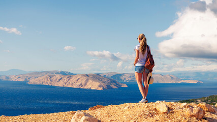 Woman standing on the edge of a cliff and looking at the sea- travel, adventure, tour tourism. Croatia