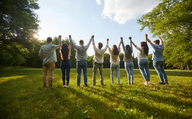 Group of friends enjoying good summer leisure days and having fun in the park. From behind several...