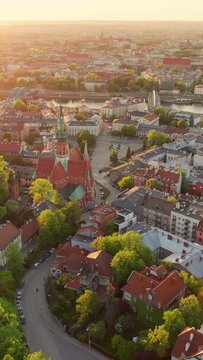 Cityscape of Krakow at sunset in summer, Poland. Aerial view of the Saint-Joseph church, Vistula river and old town of Krakow in beautiful sunset light. Aerial forward dolly