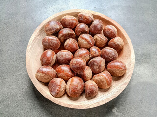 Chestnut in a wooden plate over grey background. Fresh raw chestnut. Flat lay, Top view.