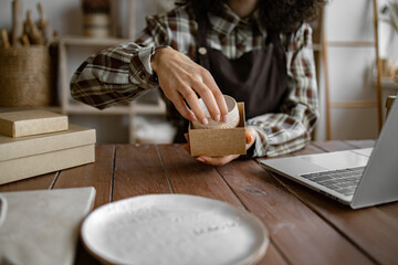 Entrepreneur sells dishes, plates and cups made of clay, ceramics online and packs them in boxes...
