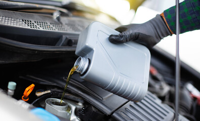 Close up photo of car mechanic or repairman is changing engine oil. Refueling and pouring oil into...