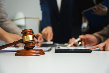 justice and law concept. team judge in a courtroom the gavel, working with digital tablet computer on wood table in sun light.