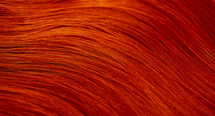 Red hair close-up as a background. Women's long orange hair. Beautifully styled wavy shiny curls....