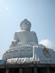 Fototapeta premium a white buddha statue on top of cement pillars with people underneath
