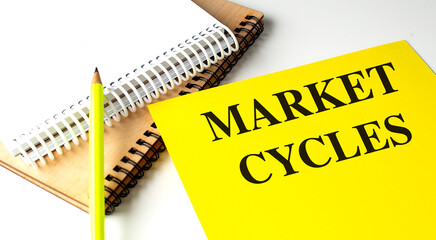 MARKET CYCLES text on yellow paper with notebooks