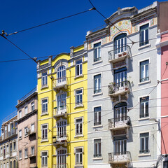 Fototapeta premium pastel-coloured and typically tiled residential buildings with the omnipresent overhead lines of the historic tramway in the Graça district of lisbon