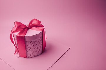 Pink ribbon-tied gift box against a pink background