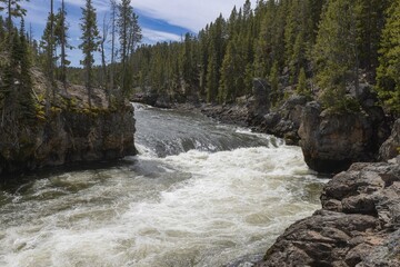 Obraz premium Rock formations and trees beside a river with two prominent rocks