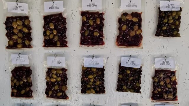 Vacuum sealed olives on a wall of a touristic shop. Slowly tilt view
