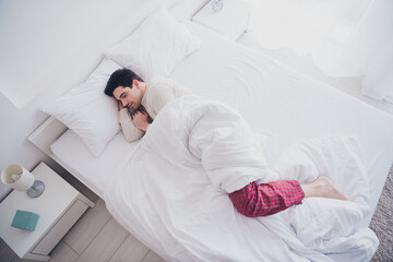 Photo of young nice man lying in soft comfy bed white bedroom interior indoors