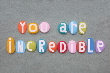 You are incredible, creative and motivational text composed with hand painted multi colored stone...