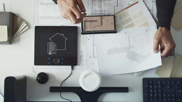 View from above. A man is designing a house. Flat lay drawings, tablet and smartphone. Interesting fresh concept