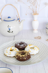 White kitchen table with some homemade donuts. Cream and chocolate donuts.