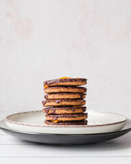 Homemade chocolate covered cookies stacked on a plate. Elegant and minimalist still life