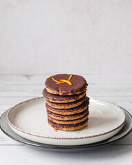 Homemade chocolate covered oatmeal cookies stacked on a plate. Elegant and minimalist still life