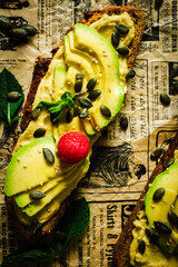 Top view of a rye bread toast with avocado and hummus.