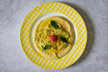 Minimalist zenithal view of a plate with hummus, avocado and mint.