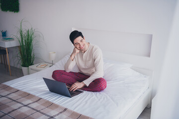 Obraz premium Photo of dreamy man sitting on bed working from home enjoy vacation white day light room indoors