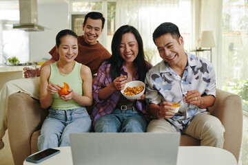 A close-knit group of friends sharing a laugh while watching a movie together in a modern and comfortable living room