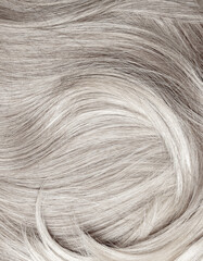Blond hair close-up as a background. Women's long blonde hair. Beautifully styled wavy shiny curls....