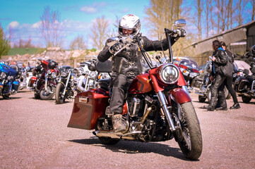 Man on a motorcycle in the street near a group during a biker show © Wirestock