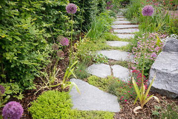 Gartenweg mit Steinplatten und vielen Pflanzen 