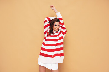 Young beautiful smiling female in trendy striped white and red sweater with holes. Carefree woman...
