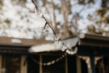 Close-up of string lights with a house in the backdrop