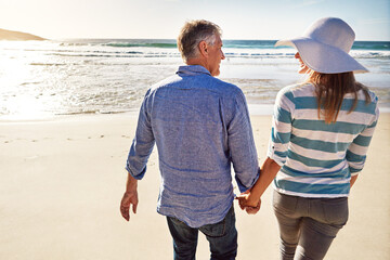 Mature couple, beach and holding hands on vacation, travel or summer holiday for love in nature....