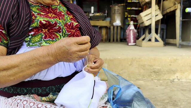 Mexican craftswoman sitting knitting in Michoacan in white cloth