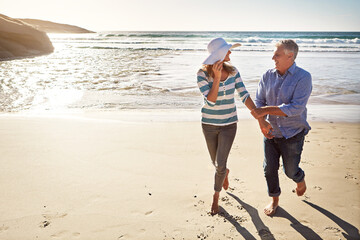 Mature couple, holding hands and walking at ocean on holiday, travel and summer sunshine on...