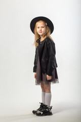 A little blonde girl in a leather jacket and a black hat