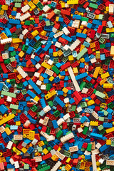 Naklejka premium A chaotic yet colorful jumble of toy bricks, tightly packed to fill the entire frame. The bricks come in various sizes and an array of colors including red, blue, green, yellow, and white,