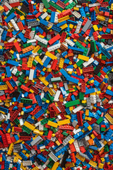 Naklejka premium A chaotic yet colorful jumble of toy bricks, tightly packed to fill the entire frame. The bricks come in various sizes and an array of colors including red, blue, green, yellow, and white,